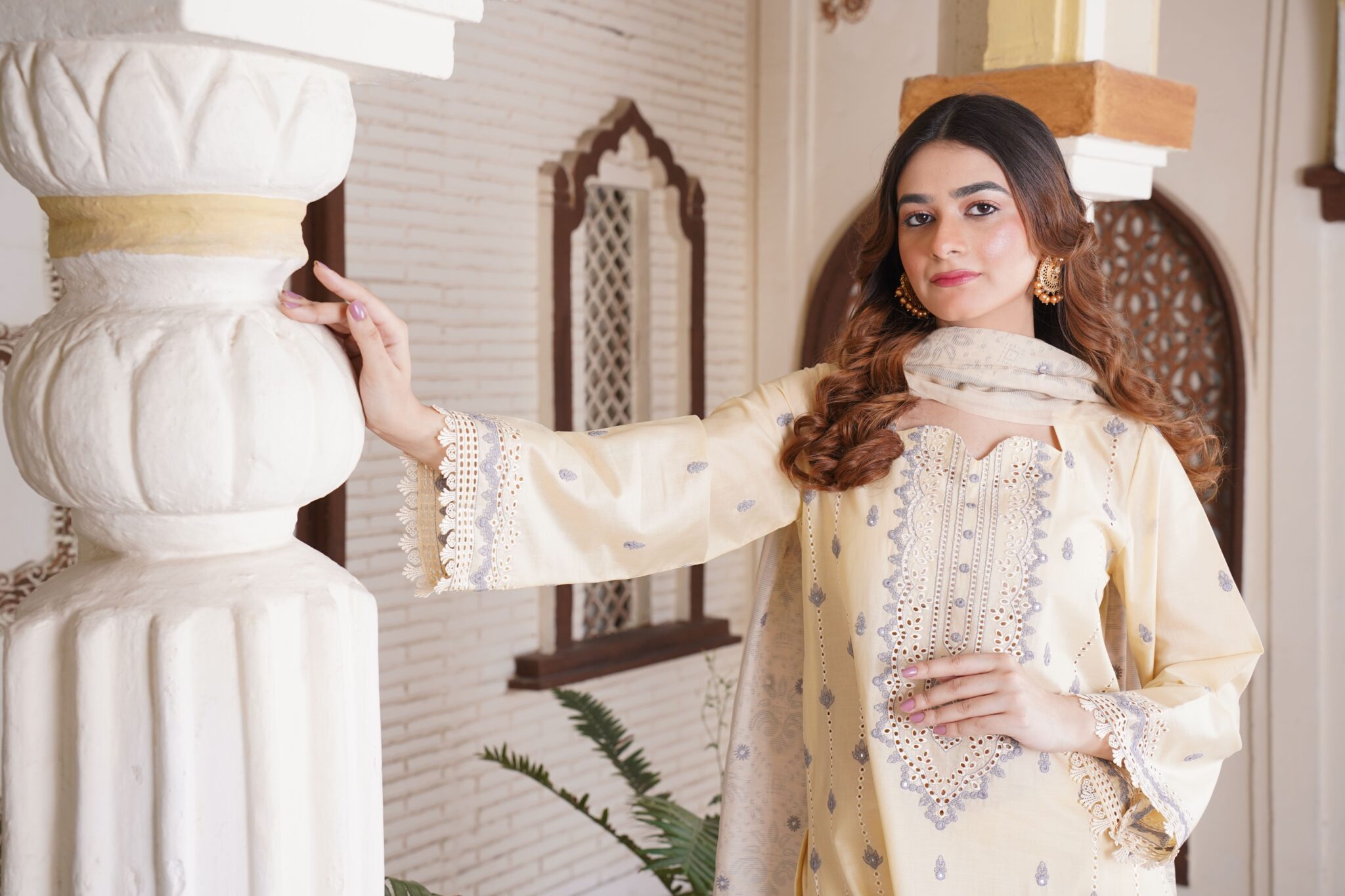 A sophisticated South Asian woman in traditional dress poses gracefully indoors in Lahore.